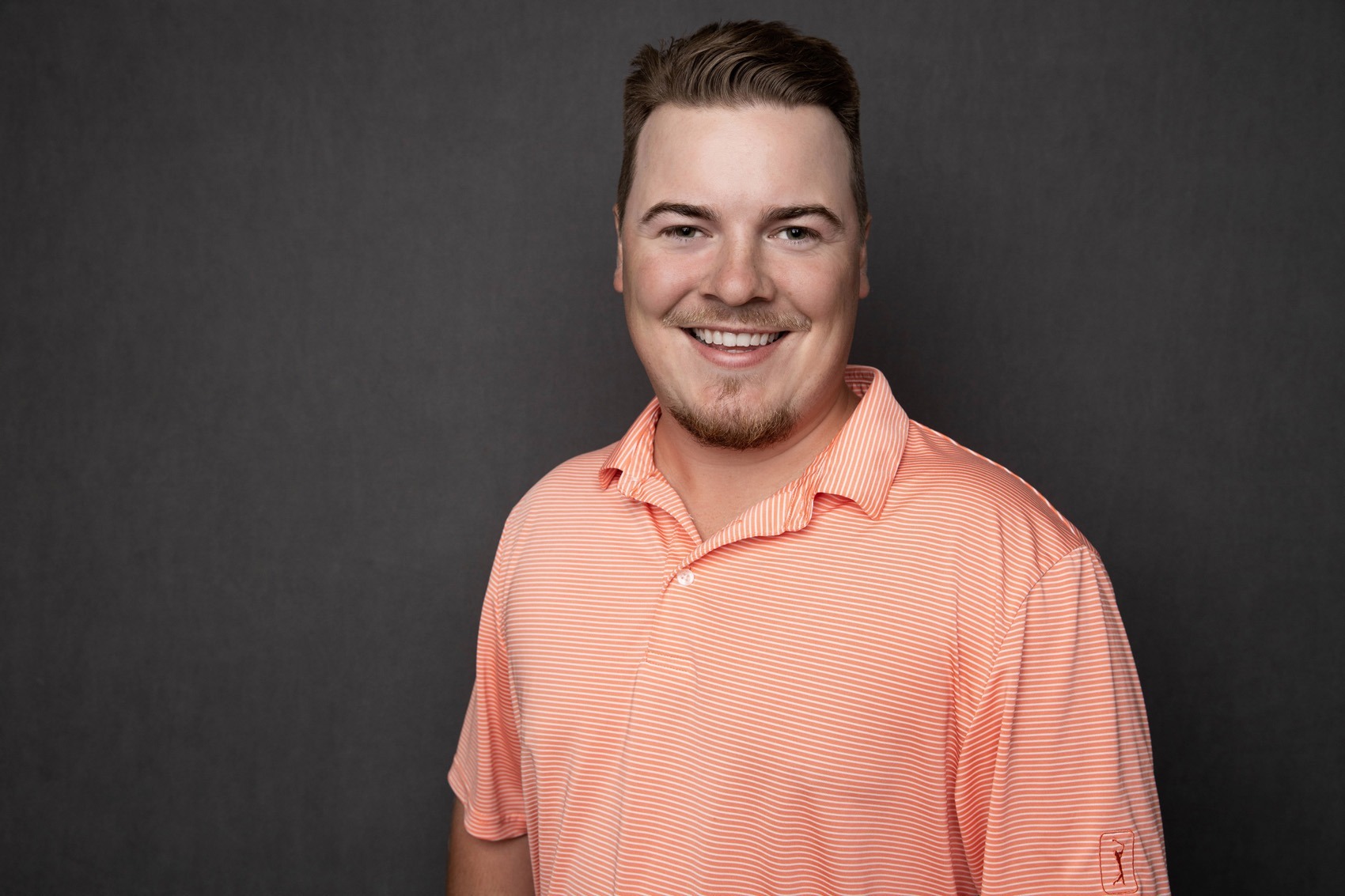 professional portrait of Scott Ellis smiling in an orange polo