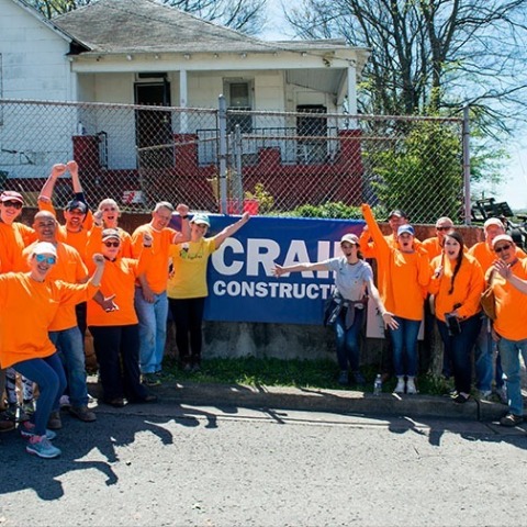crain workers wearing bright green matching shirts in a group shot in front of a company banner outside