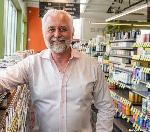 A white-haired man smiling in a local grocery store.