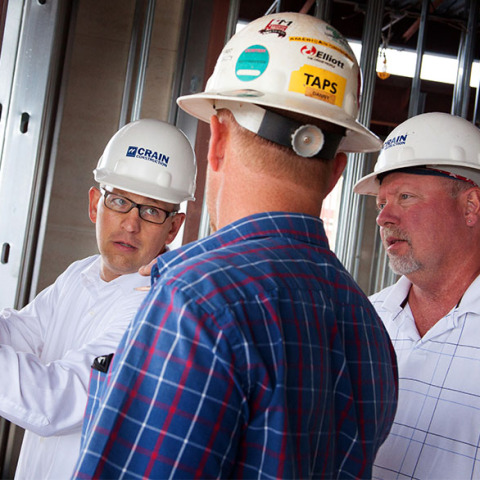 Crain construction workers in discussion wearing hard hats