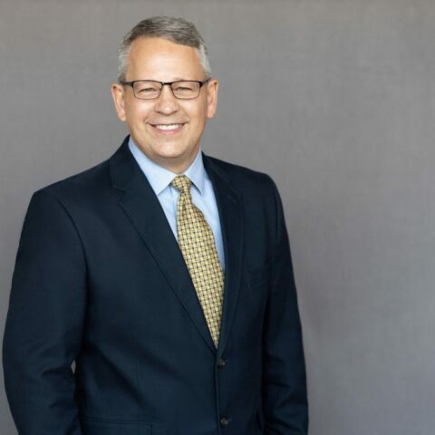 Portrait of James Williams, Senior Project Manager, in a professional setting smiling wearing a suit.