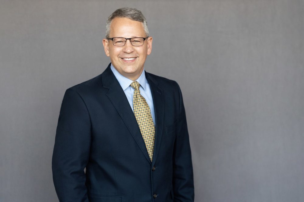 Portrait of James Williams, Senior Project Manager, in a professional setting smiling wearing a suit.