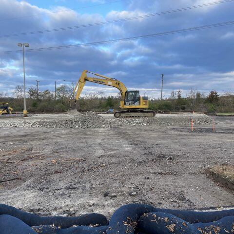 An excavator scooping gravel on a construction site.