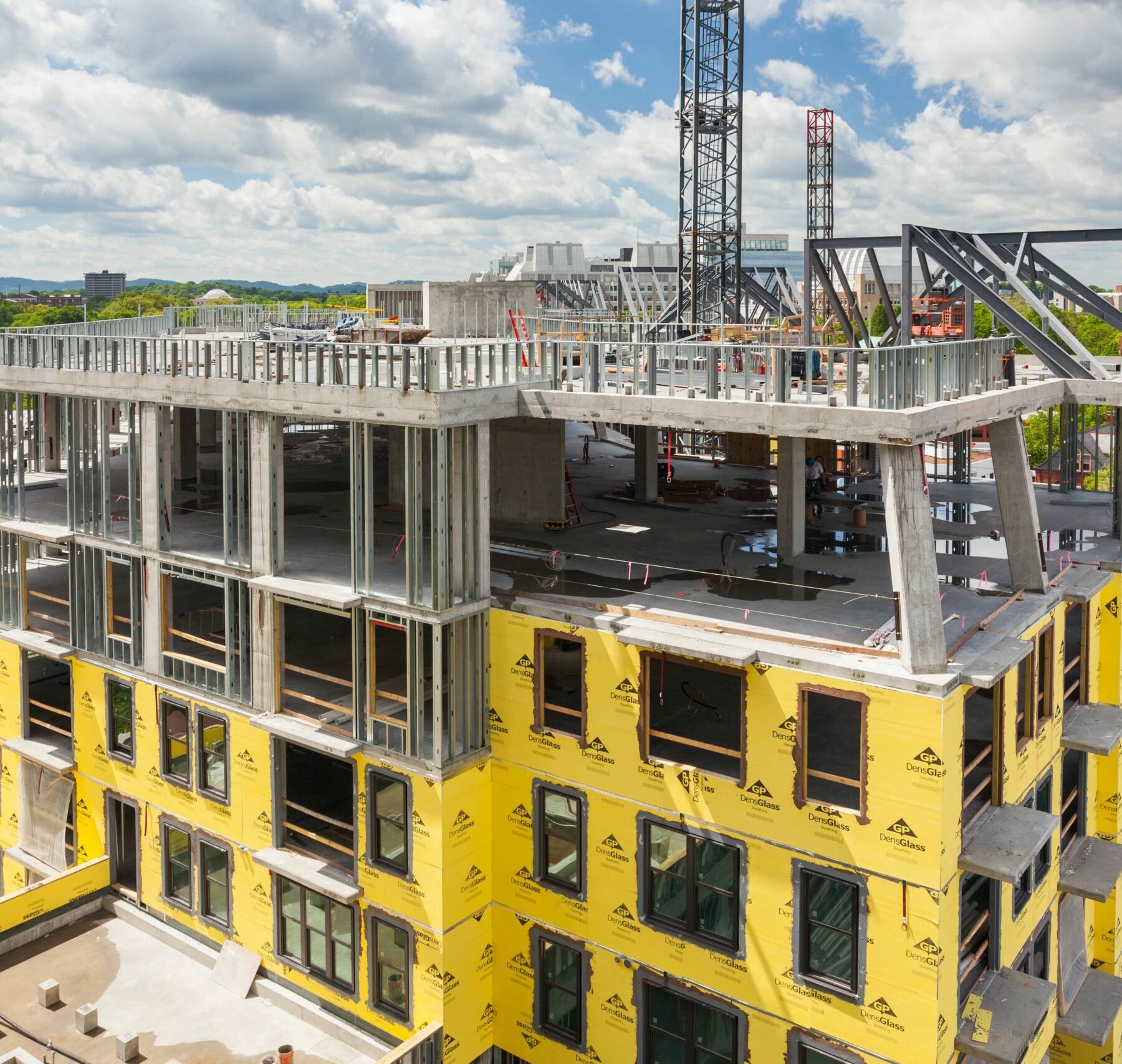 Commercial building under construction with house wrap and metal framing partially complete.