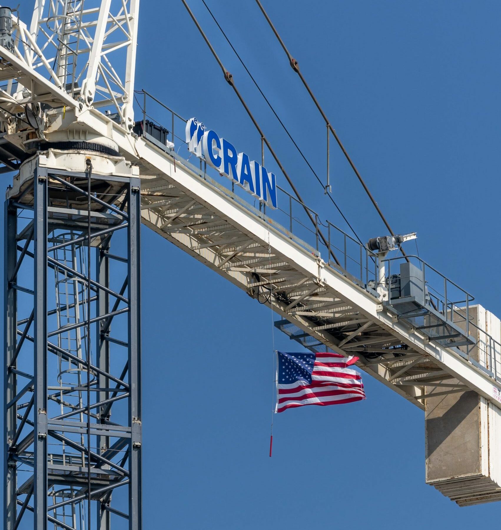 American flag hanging from a Crain Construction crain.