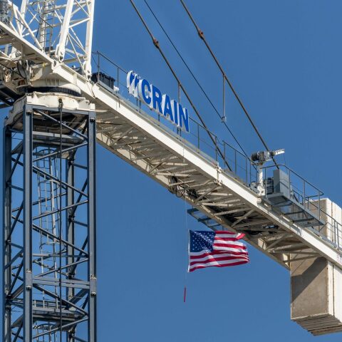 American flag hanging from a Crain Construction crain.