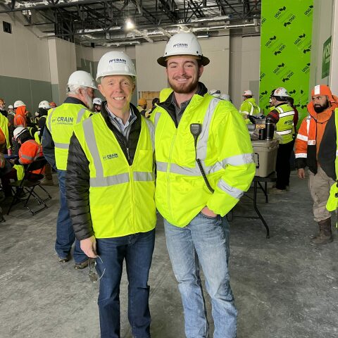 Smiling roofers in construction vests and hard hats.