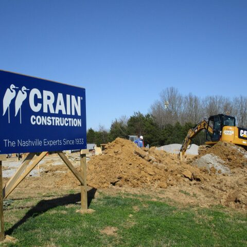 A Crain Construction sign on an active jobsite with dirt work going on behind it.