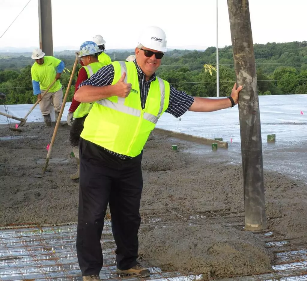 A man in a hard hat giving a thumbs up on a construction site.