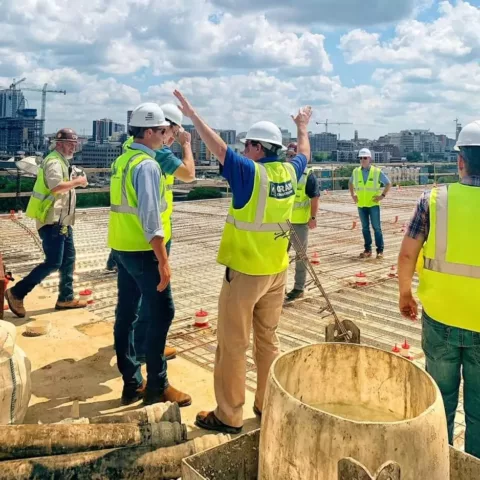 A group of construction workers, one raising his arms, on a job site.