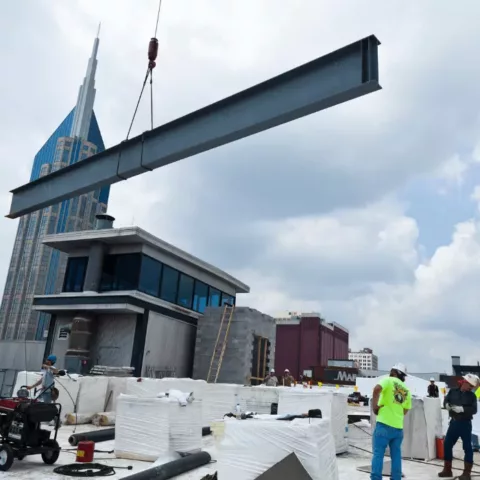 A crain placing building materials on the roof of Acme Food and Supply.