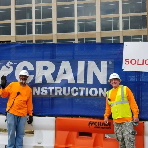 two construction workers posing in front of commercial construction project